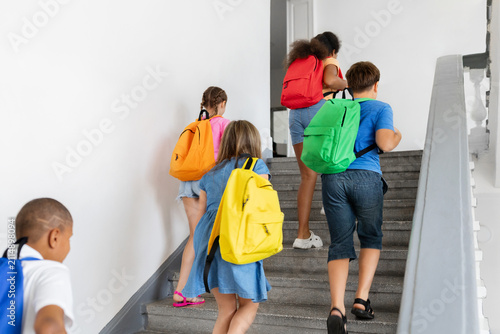 Konstfotografi Diverse schoolchildren with colorful backpacks walking upstairs together inside