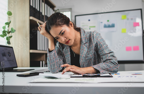 Stressed asian accountant working with financial documents in office, struggling with accounting and deadline pressure in office.
