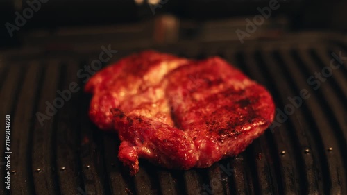 Juicy steak sizzling on a hot electric grill with visible grill marks
