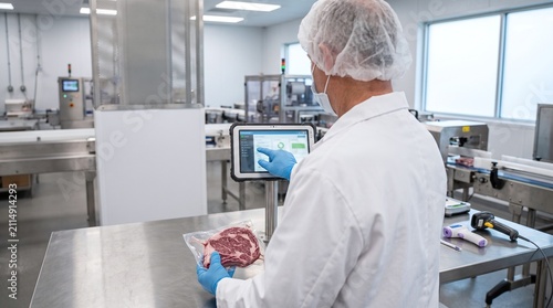 Food production worker uses digital tablet for quality control of packaged meat