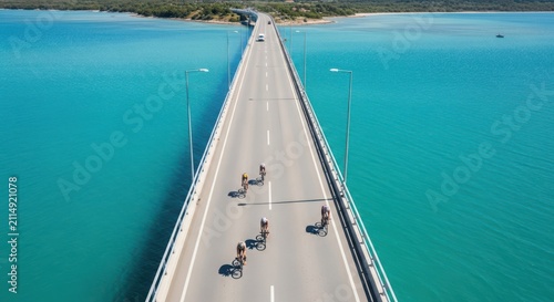 Triathlon cyclists race across a long bridge over turquoise water under bright sunlight