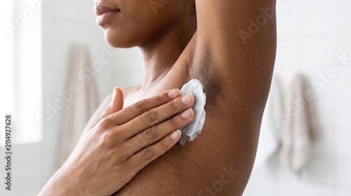 A person applies deodorant cream to their underarm, focusing on personal hygiene and skincare.
