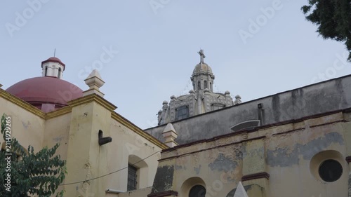 Old weathered facade of the san juan bautista parish church with its domes in coyoacan, mexico city