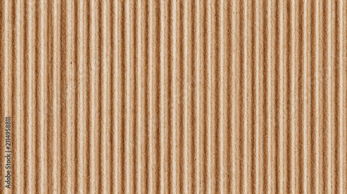 Macro texture of brown corrugated cardboard with vertical ridges forming a paper background