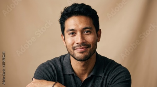 A man in a black polo shirt against a beige background.