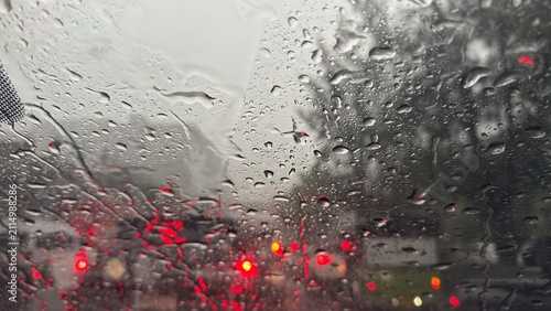 Obraz na płótnie Raindrops on window glass with blurred red traffic lights in the background