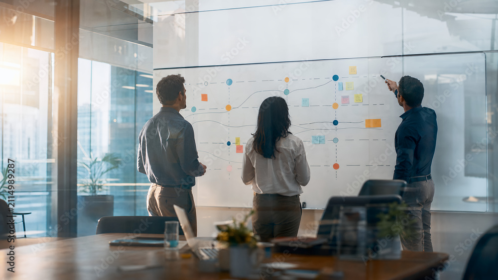 Obraz premium Business team mapping abstract strategy roadmap on large office whiteboard