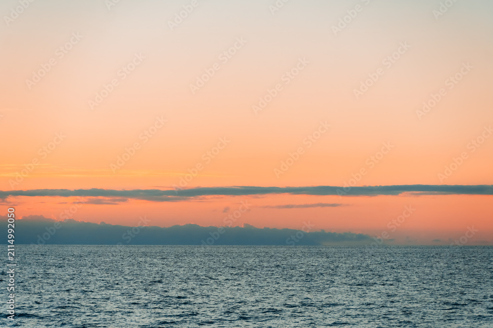 Fototapeta premium Panoramic ocean sunset with orange dusk sky gradient and calm water surface