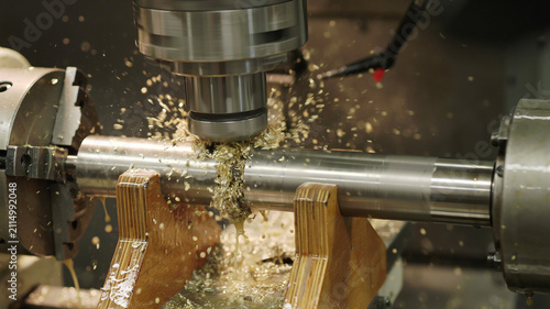 Metal rod being machined with metal shavings flying off machining