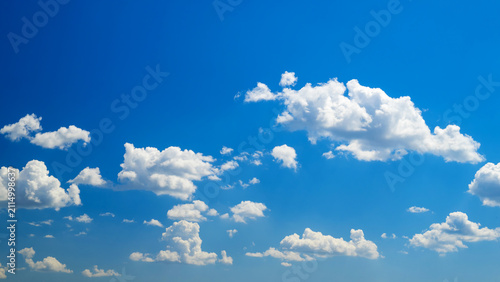 Bild auf Leinwand multiple white cumulus clouds across spacious blue sky
