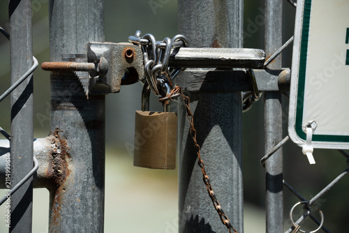 Obraz na plátně Rusty metal gate secured with a padlock and chain for security