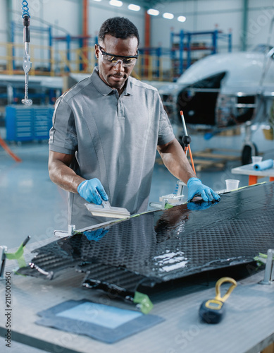 Aerospace Composite Technician Applying Carbon Fiber Resin in Aircraft Manufacturing Facility