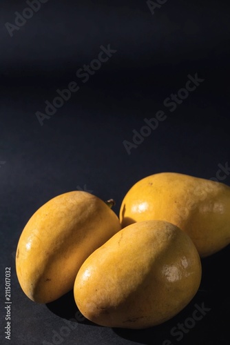 Fresh yellow mangos against a dark background