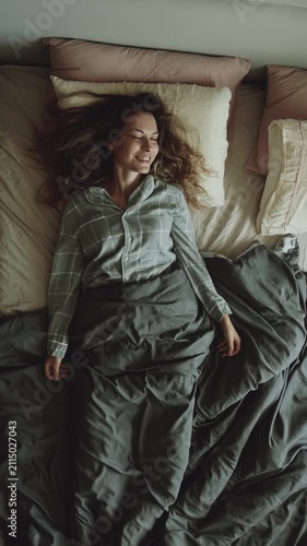 top view tired woman falls lies onto a pillow bed to rest, joy smiling face concept relax, soft mattress cozy home room. happy carefree girl is getting ready for bed have good sleep. vertical video.