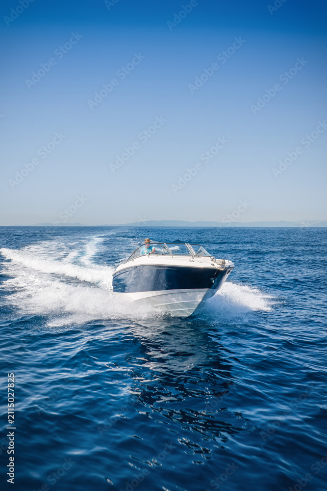 Fototapeta premium Front view of a motorboat cruising over the calm ocean with speed