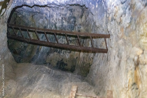 Canvastavla Exploration de l'intérieur d'une mine désaffectée du Mont Chemin en Valais, silhouette d'un explorateur près de la lumière naturelle au bout du tunnel rocheux