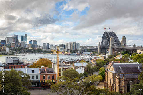 Sydney Harbour Bridge and the historic district of the Rocks on a partly cloudy autumn day. Lavender Bay and North Sydney skyline are in background.