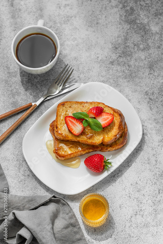 Brioche toasts with strawberry and honey on a plate on a concrete background