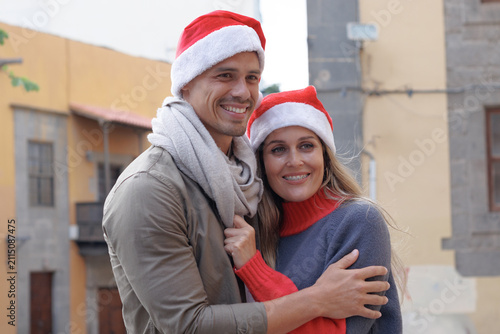 A couple wearing Santa hats and warm clothes celebrates the holidays