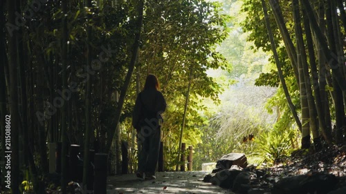Woman with backpack walking in bamboo forest path