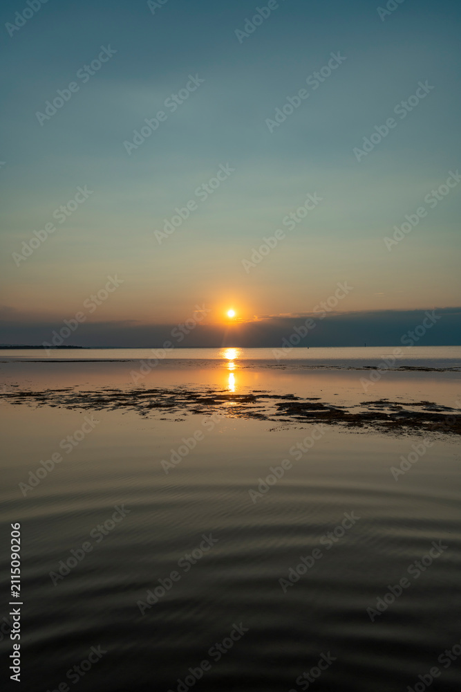 Obraz premium A serene golden sunset casting glowing reflections over the calm, shallow waters of Lake Constance as seen from the scenic Rohrspitz shore in Vorarlberg, Austria.