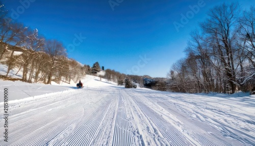 Snowy ski slope on a sunny day with clear blue sky.