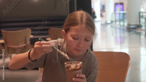 Young girl drinking a chocolate milkshake in a cafe. Child enjoying a sweet cold beverage indoors, casual lifestyle, family leisure and food concept
