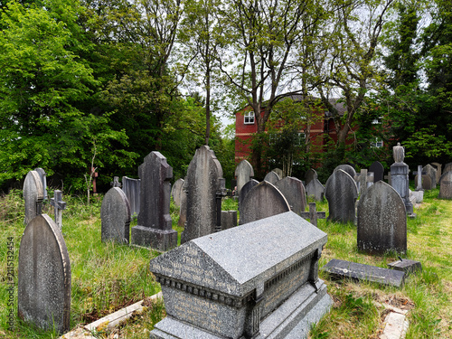 Quadro su tela Historic Manchester UK cemetery with weathered gravestones, stone sarcophagus an
