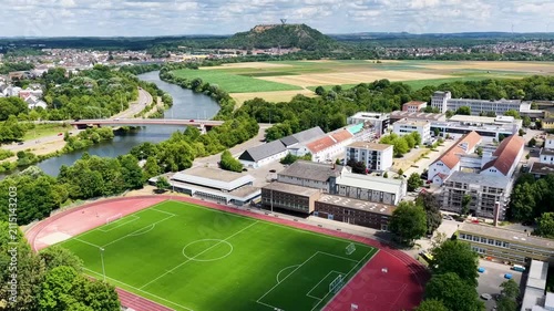 Vogelperspektive auf Saarlouis mit der vorbeifließenden Saar, einer markanten Straßenbrücke, dichter grüner Vegetation und der Stadtlandschaft unter blauem Wolkenhimmel.
