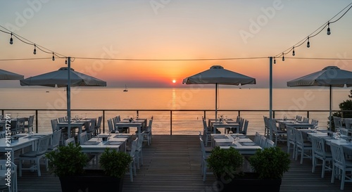 Coastal restaurant terrace overlooking a calm ocean sunset.