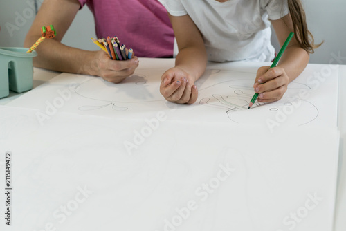 Фотография Detailed view of a left-handed student carefully drawing lines on white paper with a green pencil during home study