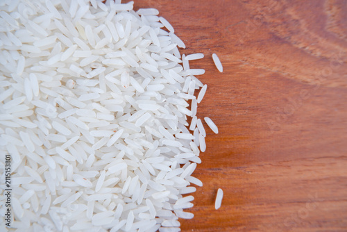 Raw white Jasmine rice grains on wooden table background with copy space