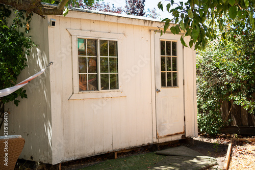 Fotografie Weathered white backyard shed with two windows and a door