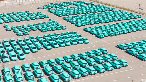 Top view of a parking lot with new turquoise electric crossover taxis.