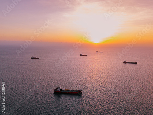 Obraz na płótnie Tanker ships with oil floating idle on calm ocean at sunset, waiting for channel