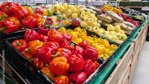 Abundance Of Fresh Red And Yellow Bell Peppers Displayed In Plastic Crates At Supermarket Produce Department