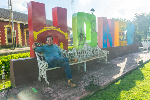 Man taking selfie at honey puebla welcome sign