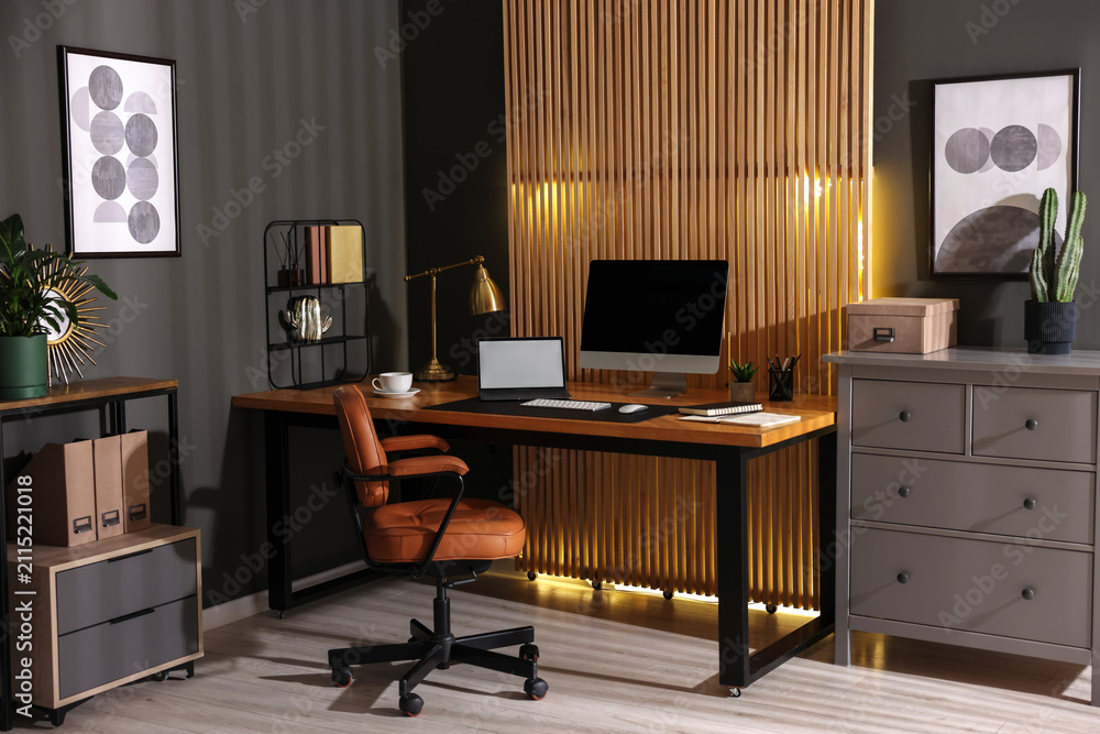 Fototapeta premium Stylish workplace with wooden desk, computer, laptop and comfortable chair in office