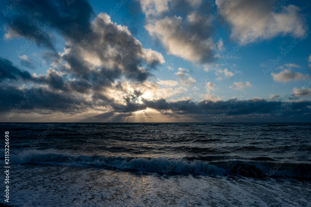 Obraz premium Dramatic Sunbeams Piercing Storm Clouds Over the North Sea