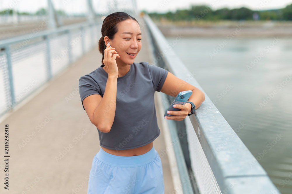 Fototapeta premium Woman listening to music on smartphone using earbuds outdoors
