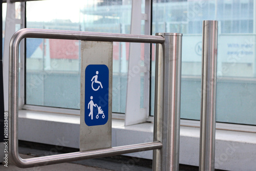 Accessible entrance gate with wheelchair and stroller access sign in modern transport terminal