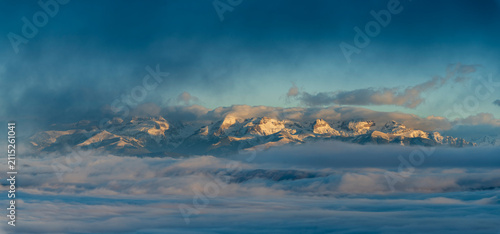 фотографія Panoramic sunrise view of Sierra Partacua in the Aragonese Pyrenees, Spain, rising above a sea of clouds during a winter temperature inversion with warm alpine light