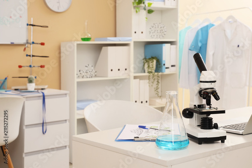 Modern laboratory interior with a microscope flask with blue liquid and lab c...