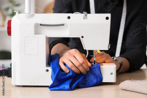 Young male tailor using sew...