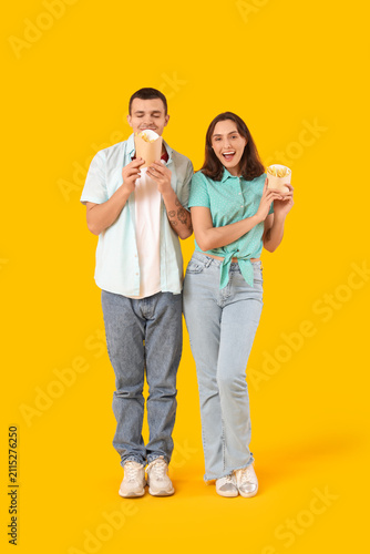 Beautiful young couple with french fries on yellow background
