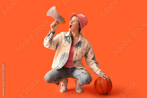 Foto Young woman with ball shouting into megaphone on red background
