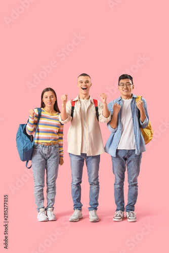 Happy students with backpacks on pink background