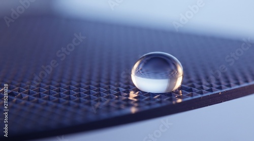 Close up of a water droplet resting on a solar wafer surface with detailed textured pattern
