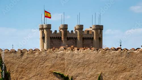 Fotografía Tower of John II at Alcazar of Segovia Castle with Spanish Flag Flying Against B