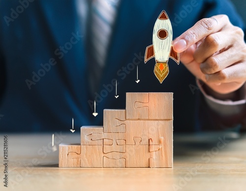 startup business launch strategy shown by a hand placing a glowing rocket puzzle piece onto a corporate foundation hierarchy